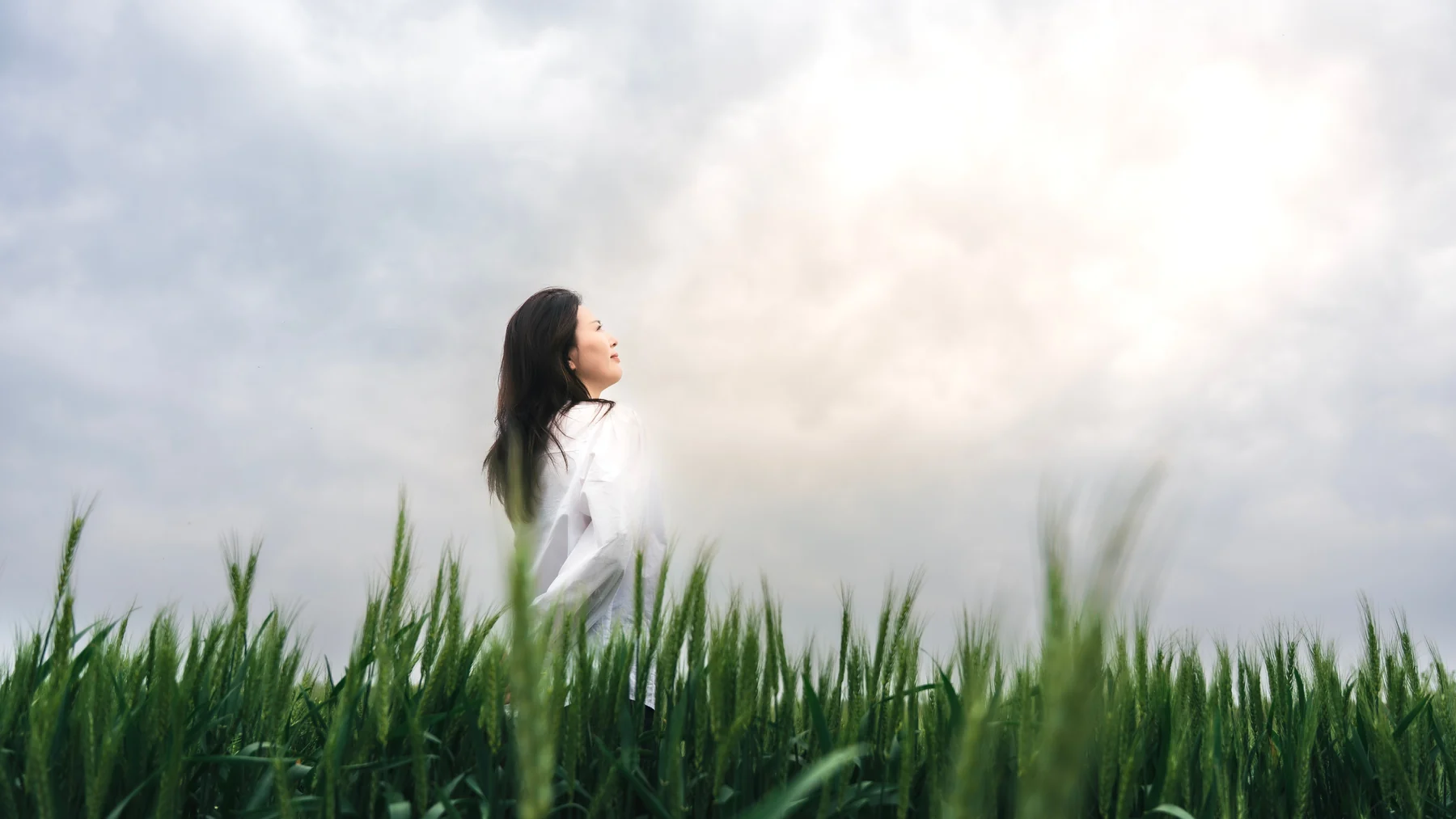 Lina standing against a pale sky beyond tall grass